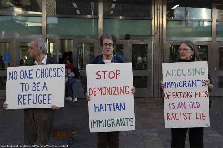 Anti-demonization of immigrants demonstrators hold signs that reads 'NO ONE CHOOSES TO BE A REFUGEE' 'STOP DEMONIZING HAITIAN IMMIGRANTS' 'ACCUSING IMMIGRANTS OF EATING PETS IS AN OLD RACIST LIE.