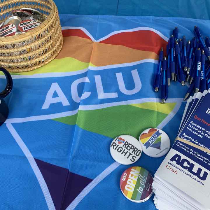 A photo of a table at Utah Pride with a table cloth that is a rainbow heart with ACLU in the center.